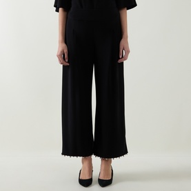 Model wearing Joseph Ribkoff Beaded Wide Leg Culottes Trousers in black with faux pearl hem detail and wide-cut legs, styled with black heels.