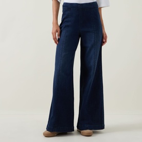 Model wearing Joseph Ribkoff dark denim blue wide-leg trousers with front seam detail, styled with white top and beige shoes.