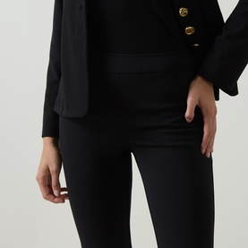 Model wearing Joseph Ribkoff black slim-fit trousers in stretch fabric, styled with a black blazer with gold buttons.