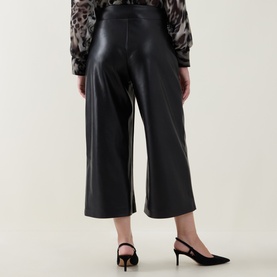 Model wearing Joseph Ribkoff black faux leather wide-leg cropped trousers, rear view, styled with black slingback heels and leopard print top.