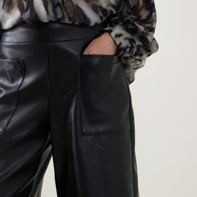 Model wearing Joseph Ribkoff black faux leather wide-leg trousers with patch pockets, styled with a monochrome printed blouse.