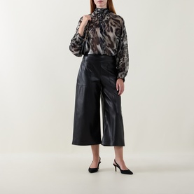 Model wearing Joseph Ribkoff black wide-leg culottes in faux leather finish, styled with a leopard-print blouse and black slingback heels.