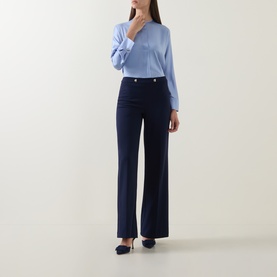 Model wearing Joseph Ribkoff Indigo wide-leg trousers with silver button detail, styled with a light blue top and navy heels.