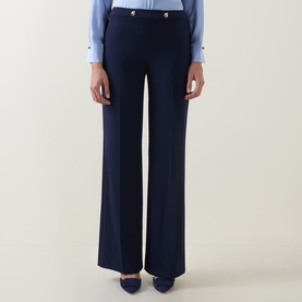 Model wearing Joseph Ribkoff indigo wide-leg trousers with gold-tone button waist detail, styled with a light blue shirt and navy heels.
