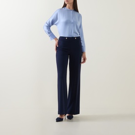 Model wearing Joseph Ribkoff indigo wide-leg trousers with silver-tone buttons, styled with a light blue top and navy heels.