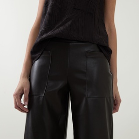 Model wearing Joseph Ribkoff Faux Leather Culottes Trousers in Mocha, wide-leg silhouette with front patch pockets, styled with a dark knit vest.
