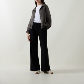 Model wearing Joseph Ribkoff Tailored Wide Leg Trousers in black with wide-cut legs and pleated details, styled with a khaki zip jacket and white tee.