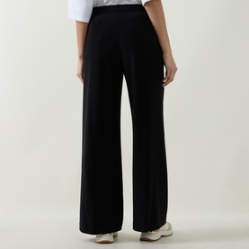 Model wearing Joseph Ribkoff Tailored Wide Leg Trousers in black, styled with white trainers, showing wide-cut legs and elasticated waistband from