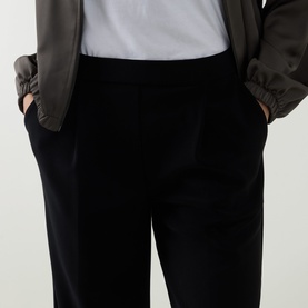 Model wearing Joseph Ribkoff Tailored Wide Leg Trousers in black with elasticated waistband and side pockets, styled with an olive bomber jacket.
