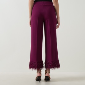 Model wearing Joseph Ribkoff Feather-Trim Cropped Trousers in Berry Burst, back view, with sequin-embellished faux feather cuffs, styled with black