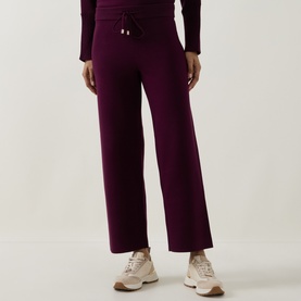 Model wearing Joseph Ribkoff Brushed Knit Track Pants in Elderberry, straight-leg cut with drawstring waistband, styled with white trainers.