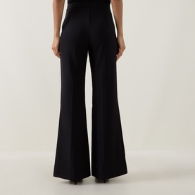 Model wearing Joseph Ribkoff black wide-leg trousers, rear view, styled with a black top. High-waisted with flared hem.