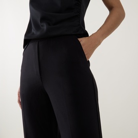 Model wearing Joseph Ribkoff black wide-leg trousers with side pockets, styled with a black sleeveless top.