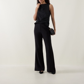 Model wearing Joseph Ribkoff black wide-leg trousers, styled with a matching sleeveless top and black heels, carrying a small black clutch.