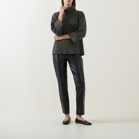Model wearing Joseph Ribkoff black faux leather slim-leg trousers, styled with a dark high-neck top and black ballet flats.