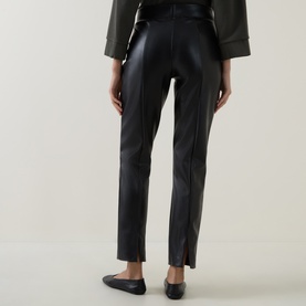 Model wearing Joseph Ribkoff black faux leather slim-leg trousers, rear view, styled with khaki top and black ballet flats.