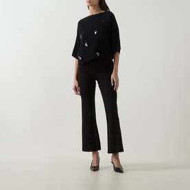 Model wearing Joseph Ribkoff Embellished Flared-Leg Trousers in black with pull-on waist, styled with matching black embellished top and heels.