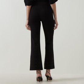 Model wearing Joseph Ribkoff Embellished Flared-Leg Trousers in black, mid-rise pull-on style, shown from behind with black heeled mules.