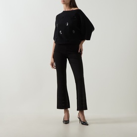 Model wearing Joseph Ribkoff Embellished Flared-Leg Trousers in black, paired with a black batwing top and black heels.