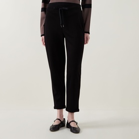 Model wearing Joseph Ribkoff black tapered trousers with drawstring waist, styled with a sheer striped top and black ballet flats.