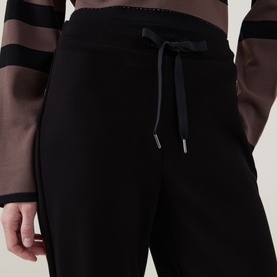 Model wearing Joseph Ribkoff black drawstring trousers with elasticated waistband, styled with a striped black and brown top.