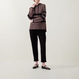 Model wearing Joseph Ribkoff black tapered trousers, styled with a dark mauve colour-block hoodie and black flat shoes.