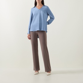 Model wearing Joseph Ribkoff Pleated Straight Leg Trousers in Mink, straight leg fit with pleated front, styled with a blue long-sleeve top and nude