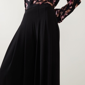 Model wearing Joseph Ribkoff black wide-leg trousers with pleated front, styled with a pink floral print blouse.