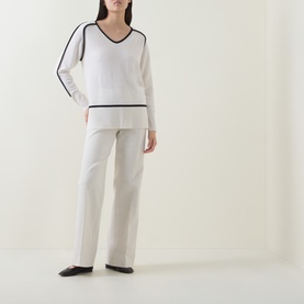 Model wearing Joseph Ribkoff winter white and black wool-cashmere tunic with V-neck and contrast stripe trim, styled with wide-leg white trousers