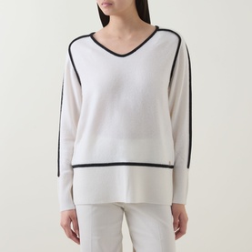Model wearing Joseph Ribkoff winter white and black contrast-trim wool cashmere tunic with v-neck and stripe sleeve detail, styled with light trousers
