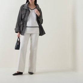 Model wearing Joseph Ribkoff Winter White and Black wool-cashmere tunic, styled with grey jacket, cream trousers, and black flats, carrying small