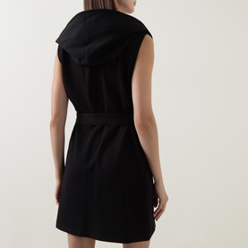 Model wearing Joseph Ribkoff black sleeveless hooded vest dress, rear view, fitted silhouette with hood detail