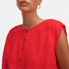 Model wearing Forever New Cherry Tomato dress with keyhole neckline and button detail, styled with gold hoop earrings.