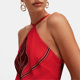 Model wearing Forever New red halterneck dress with leaf embroidery detail and ruffle trim, styled with gold hoop earrings.