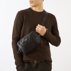 Model carrying Prada Bandoliera Logo Messenger Bag in brown distressed nappa leather, worn as crossbody with adjustable strap, styled with dark brown