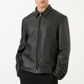 Model wearing Prada black nappa leather casual jacket with zip front, spread collar, and chest pocket, styled with black trousers.