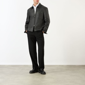 Model wearing Prada black nappa leather casual jacket with white shirt and black tailored trousers, styled with chunky black loafers.