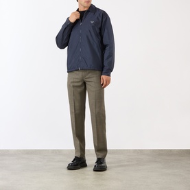 Model wearing Prada Triangle Logo Zip Overshirt in blue Re-Nylon, styled with khaki trousers and black loafers