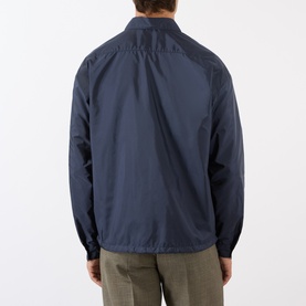 Model wearing Prada Triangle Logo Zip Overshirt in blue Re-Nylon, back view, styled with khaki trousers