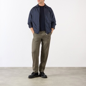 Model wearing Prada Triangle Logo Zip Overshirt in blue Re-Nylon, styled with khaki trousers and black loafers.