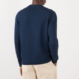 Model wearing Prada Logo Knit Sweater in navy cotton, crew neck, raglan shoulders, ribbed trims. Styled with cream trousers.