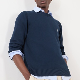 Model wearing Prada Logo Knit Sweater in navy, crew neck with embroidered logo, styled over a light blue striped shirt.
