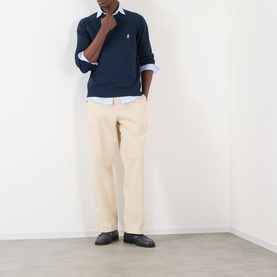 Model wearing Prada Logo Knit Sweater in navy, crew neck with embroidered logo, styled with cream trousers and light blue shirt.