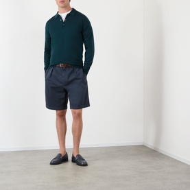 Model wearing Prada Classic Gabardine Shorts in blue with pleated front, styled with a dark green polo and navy loafers.
