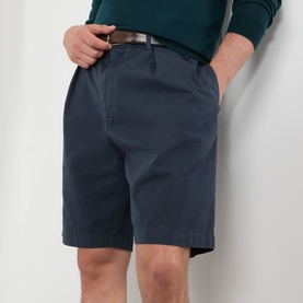 Model wearing Prada Classic Gabardine Shorts in blue with pleated detail and belt loops, styled with a brown belt and teal knit top.