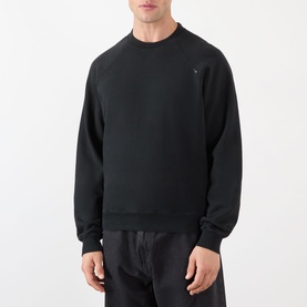 Model wearing Prada Logo Raglan Sweatshirt in black with round neck, raglan sleeves, and ribbed trims, styled with black trousers.