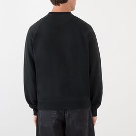 Model wearing Prada Logo Raglan Sweatshirt in black, rear view, showing raglan sleeves and ribbed trims, styled with dark jeans.