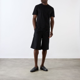 Model wearing Prada black cotton T-shirt with black wide-leg shorts and black loafers.