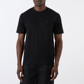 Model wearing Prada black cotton crew-neck T-shirt with tonal logo embroidery at chest, styled with black trousers