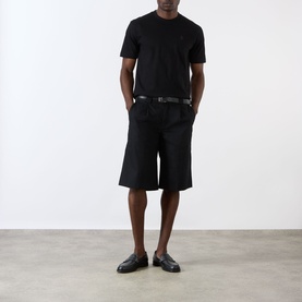 Model wearing Prada black cotton T-shirt, styled with black shorts, belt and loafers.
